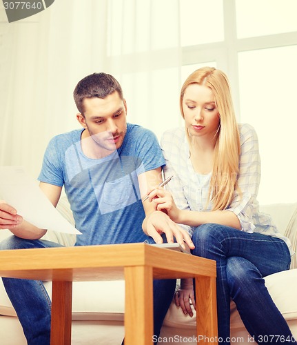 Image of busy couple with papers and calculator at home