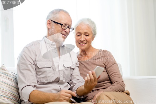 Image of happy senior couple with smartphone at home