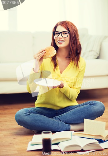 Image of student eating hamburger and doing homework