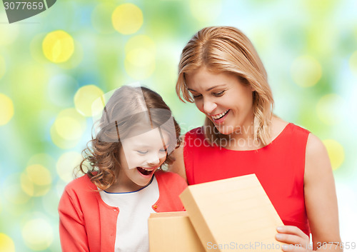 Image of happy mother and daughter opening gift box