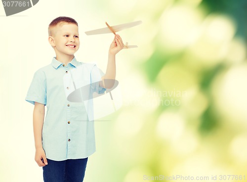 Image of smiling little boy holding a wooden airplane model