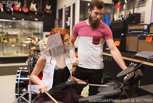 Image of man and woman with drum kit at music store