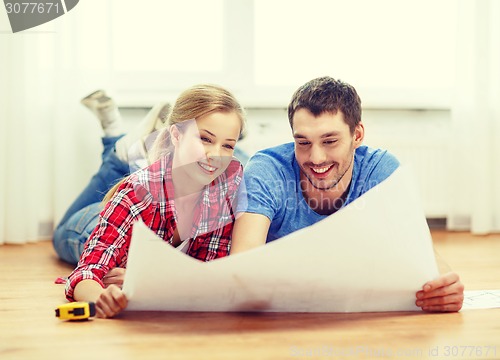 Image of smiling couple looking at blueprint at home