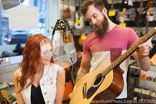 Image of couple of musicians with guitar at music store