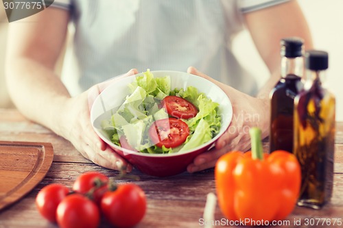 Image of close of male hand holding a bowl with salad