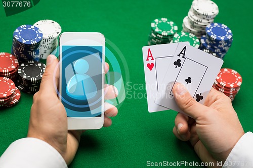 Image of casino player with cards, smartphone and chips