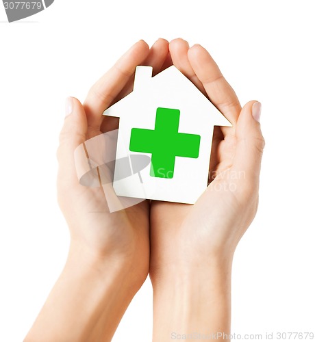 Image of hands holding paper house with green cross