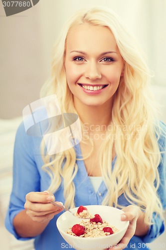 Image of smiling woman with bowl of muesli having breakfast