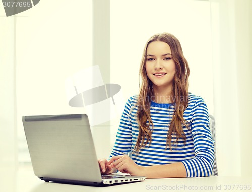 Image of smiling teenage gitl with laptop computer at home