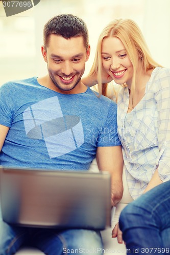 Image of smiling happy couple with laptop at home