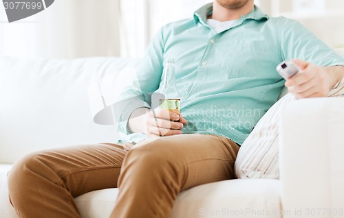 Image of man with beer and remote control at home