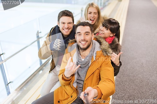 Image of happy friends taking selfie on skating rink