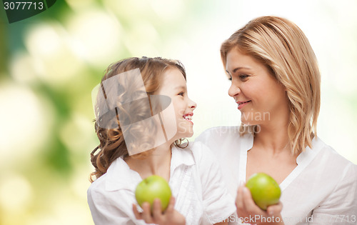 Image of happy mother and daughter with green apples
