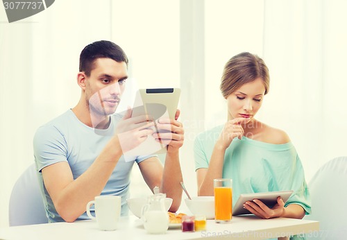 Image of concentrated couple with tablet pc reading news