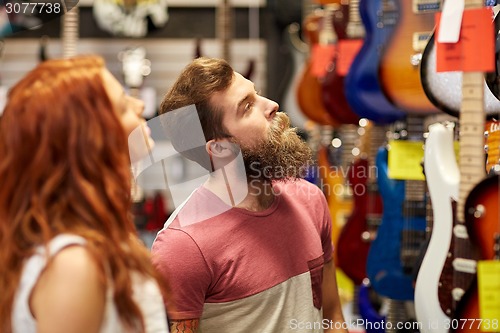 Image of couple of musicians with guitar at music store