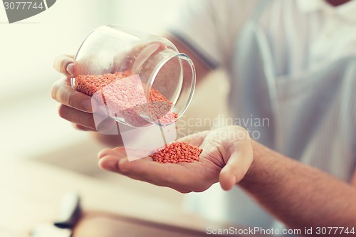 Image of close up of male emptying jar with red lentils