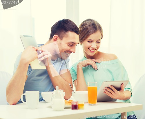 Image of smiling couple with tablet pc reading news