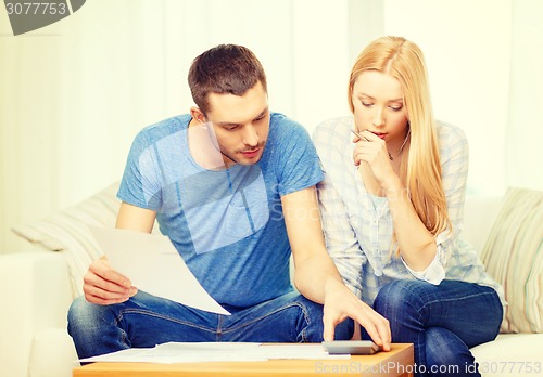 Image of busy couple with papers and calculator at home