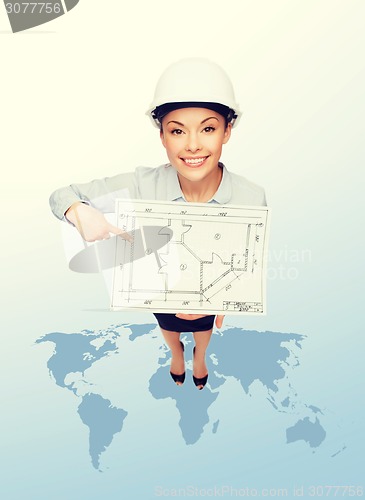 Image of businesswoman in helmet showing with blueprint