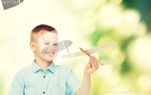 Image of smiling little boy holding a wooden airplane model