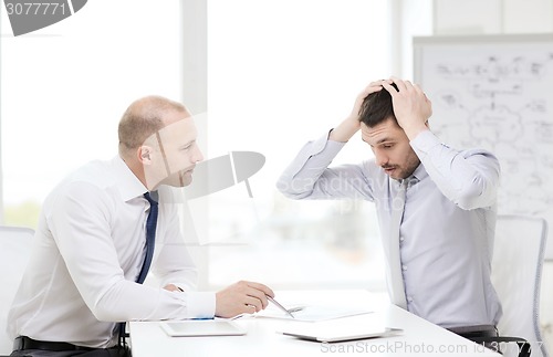 Image of two serious businessmen with tablet pc in office