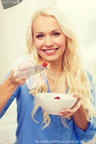 Image of smiling woman with bowl of muesli having breakfast