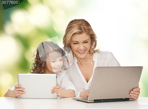 Image of mother with girl looking to laptop and tablet pc