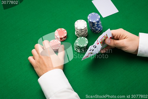 Image of poker player with cards and chips at casino