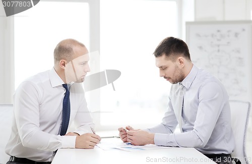 Image of two serious businessman with papers in office