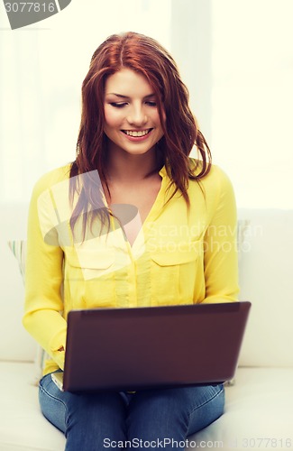 Image of smiling woman with laptop computer at home