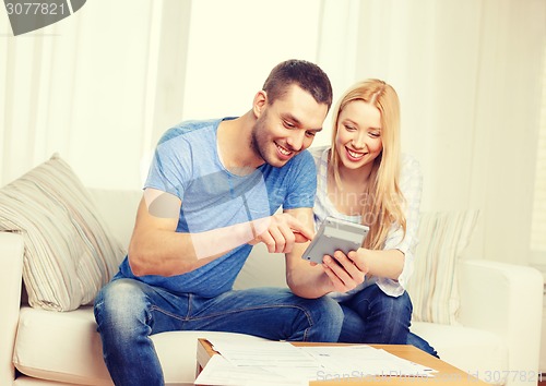 Image of smiling couple with papers and calculator at home