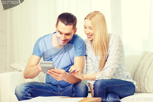 Image of smiling couple with papers and calculator at home