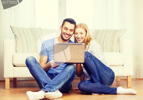 Image of smiling happy couple with laptop at home