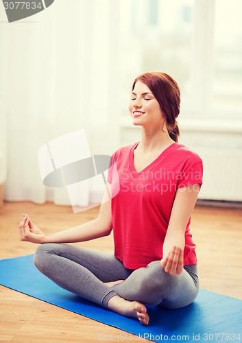 Image of smiling redhead teenager meditating at home