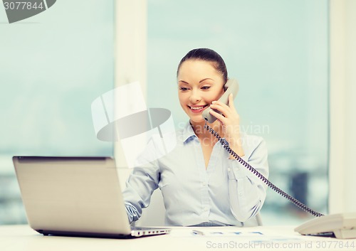 Image of businesswoman with phone, laptop and files