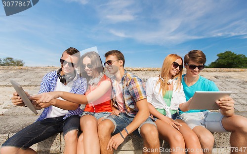 Image of group of smiling friends with tablet pc outdoors