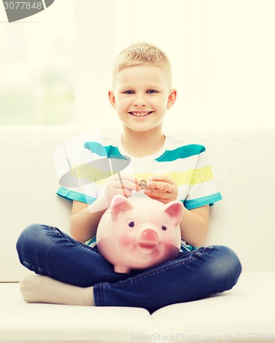 Image of smiling little boy with piggy bank and money