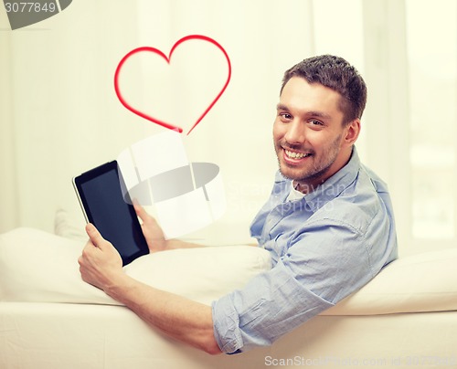 Image of smiling man working with tablet pc at home