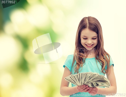 Image of smiling little girl looking at dollar cash money