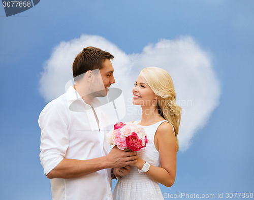 Image of happy couple with flowers over heart shaped cloud