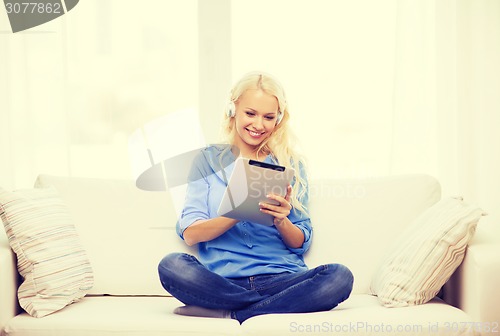 Image of woman with tablet pc and headphones at home