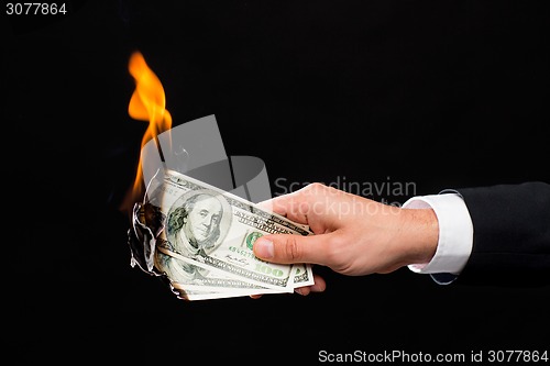 Image of close up of male hand holding burning dollar money