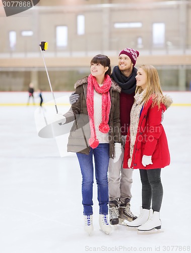 Image of happy friends with smartphone on skating rink