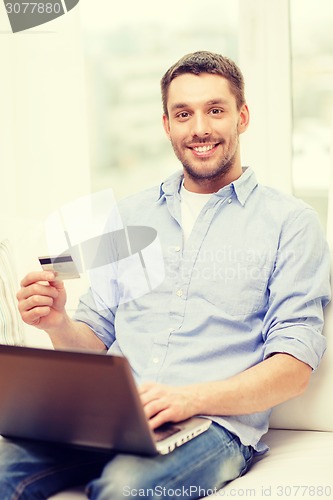 Image of smiling man working with laptop and credit card