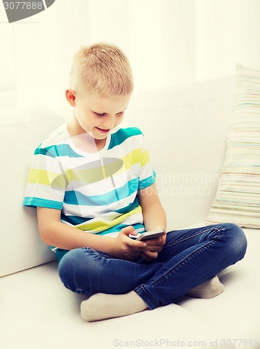Image of smiling little boy with smartphone at home