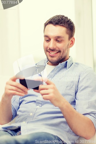 Image of smiling man with smartphone at home