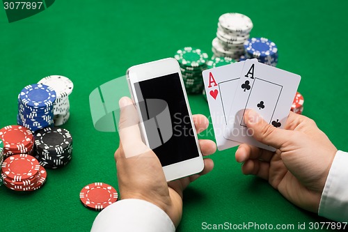 Image of casino player with cards, smartphone and chips