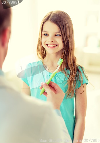 Image of male doctor giving toothbrush to smiling girl