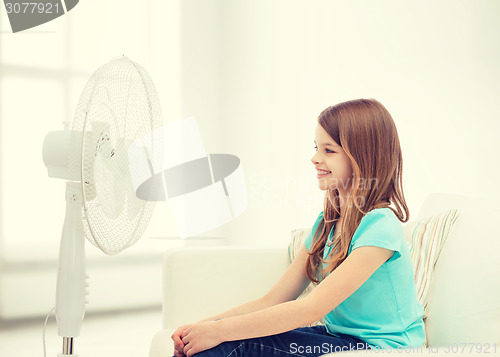 Image of smiling little girl with big fan at home