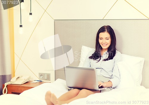 Image of happy businesswoman with laptop in hotel room